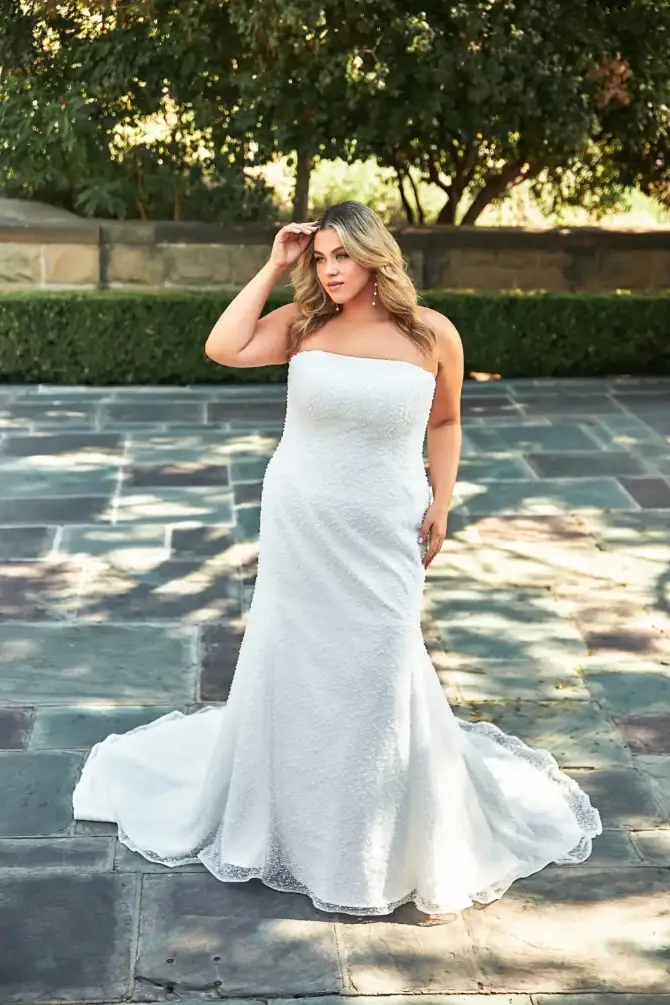 model is wearing a plus size strapless fit and flare wedding gown
