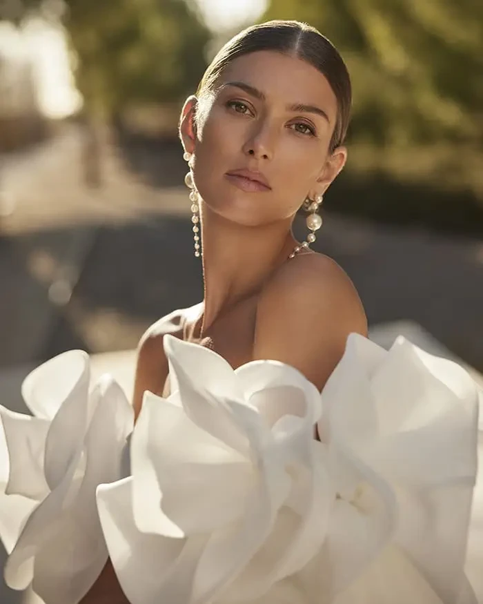 Model is wearing a strapless stretch mikado mermaid gown with detachable sleeves and a fitted silhouette.