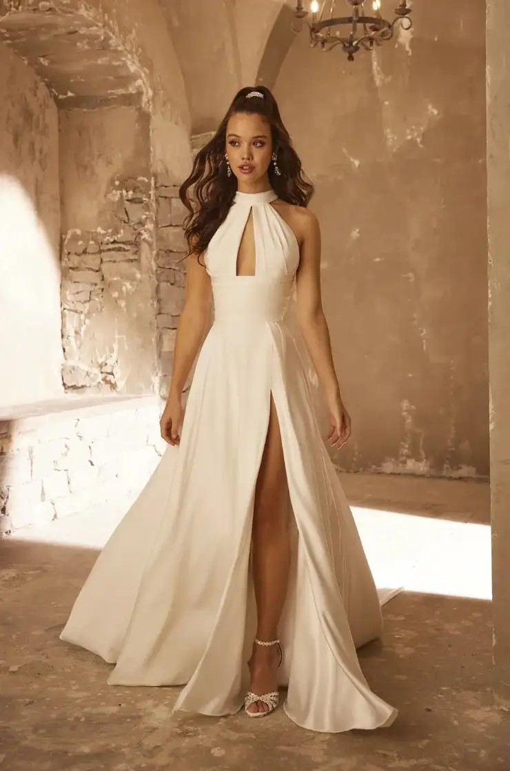 Model is wearing a fit and flare halter bridal gown with exposed boning by paloma blanca