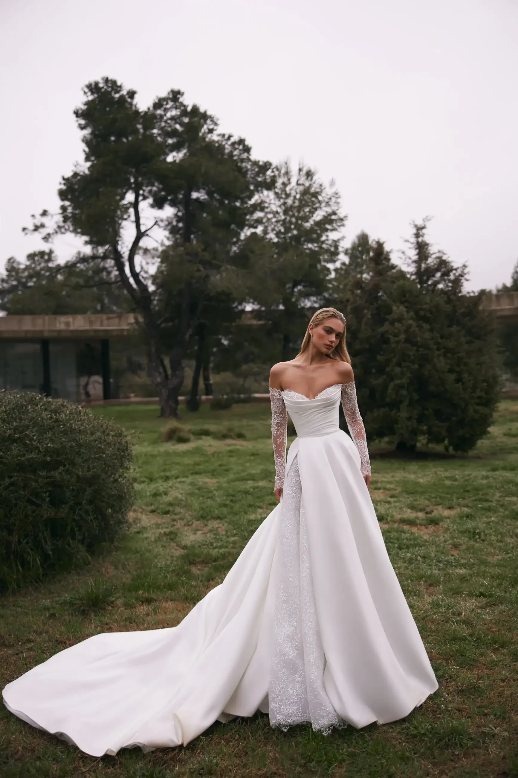 model is wearing an off the shoulder long sleeve a-line bridal dress