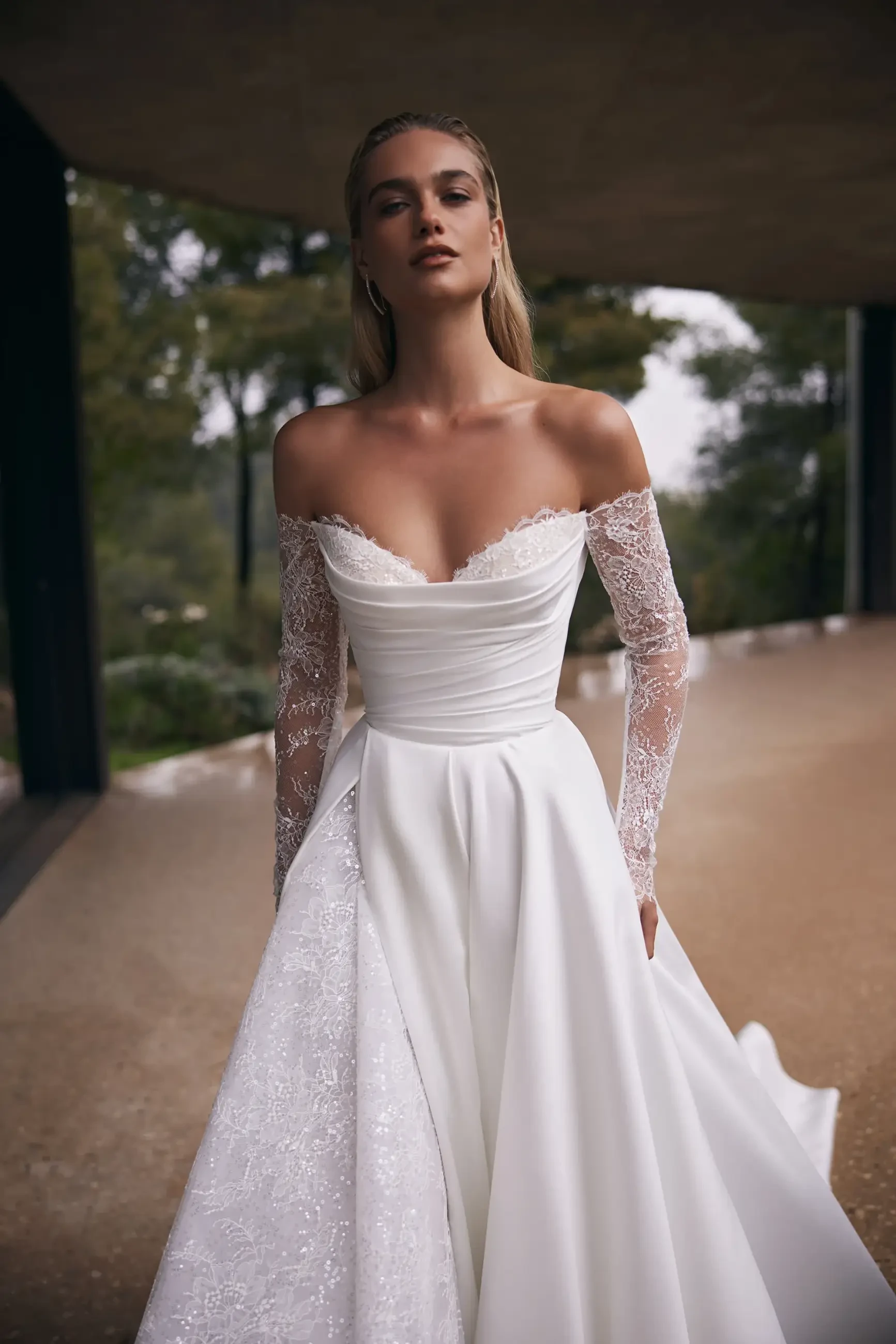 model is wearing an off the shoulder long sleeve a-line bridal dress