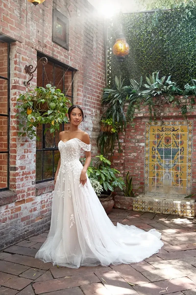 model is wearing an off the shoulder a-line bridal gown