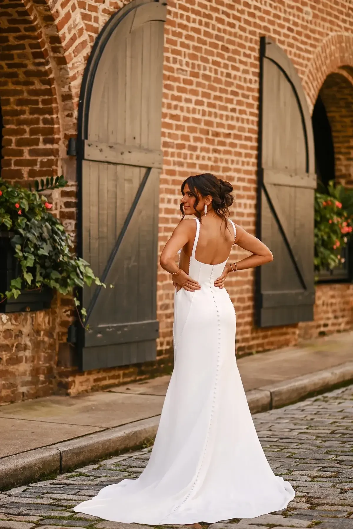 Model is wearing a crepe sheath gown with a square neckline, sheer side cutouts, pearl-beaded seams, and a sleek column silhouette.