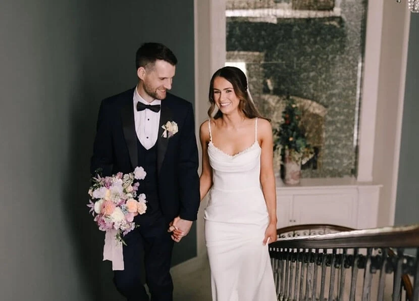 Сouple wearing a white gown and a black suit on the stairs