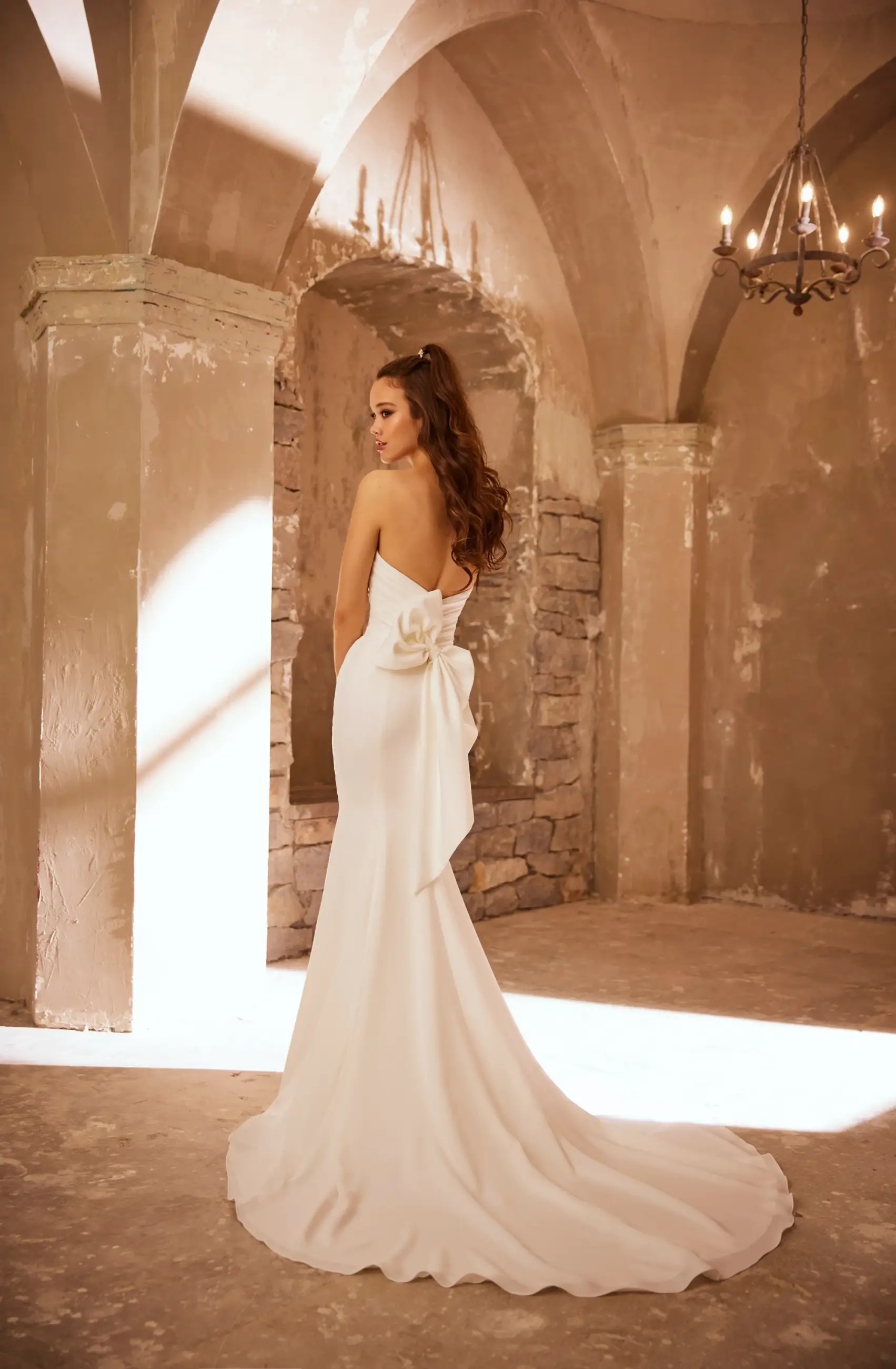 Model is wearing a fit and flare wedding dress with a draped bodice and sweetheart neckline by paloma blanca